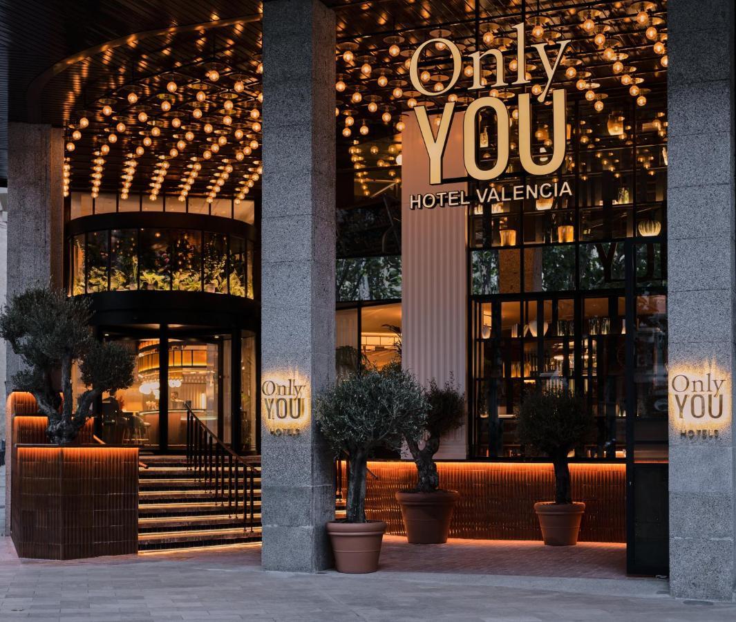 Only You Hotel Valencia Luaran gambar The photo shows the entrance of a hotel named "Only YOU Hotel Valencia." The facade is modern and stylish, featuring a large, well-lit sign with the hotel name prominently displayed. The entrance is adorned with decorative lighting overhead, creating